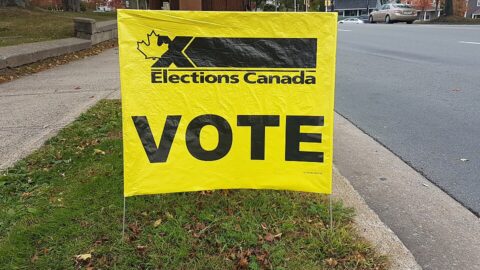 Yellow Elections Canada VOTE sign on a street lawn