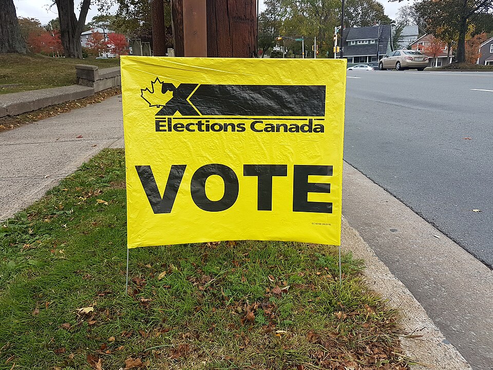 Yellow Elections Canada VOTE sign on a street lawn