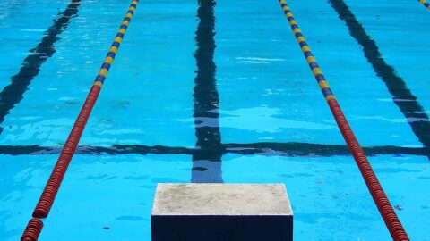 Empty competition swimming pool lanes with a starting block in the foreground