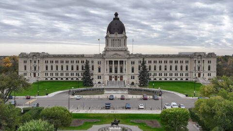 The Saskatchewan Legislative Building in Regina with lawns and parked cars in front